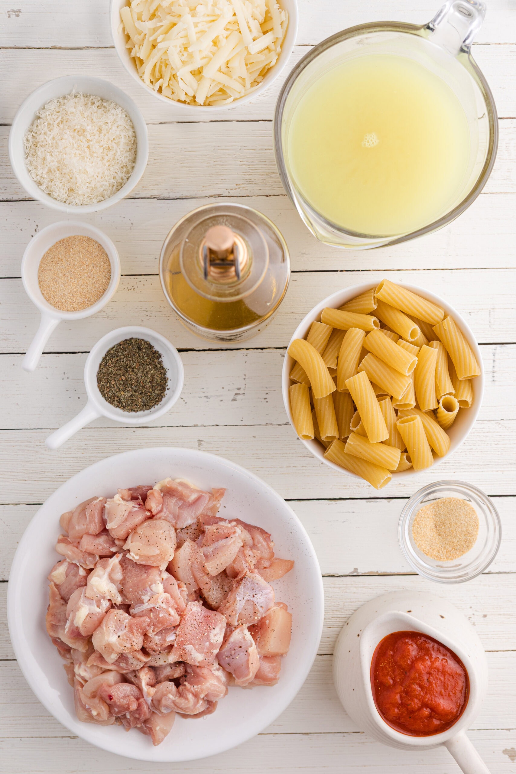 one pot chicken parmesan pasta ingredients including chicken thighs, marinara sauce, pasta, and cheese