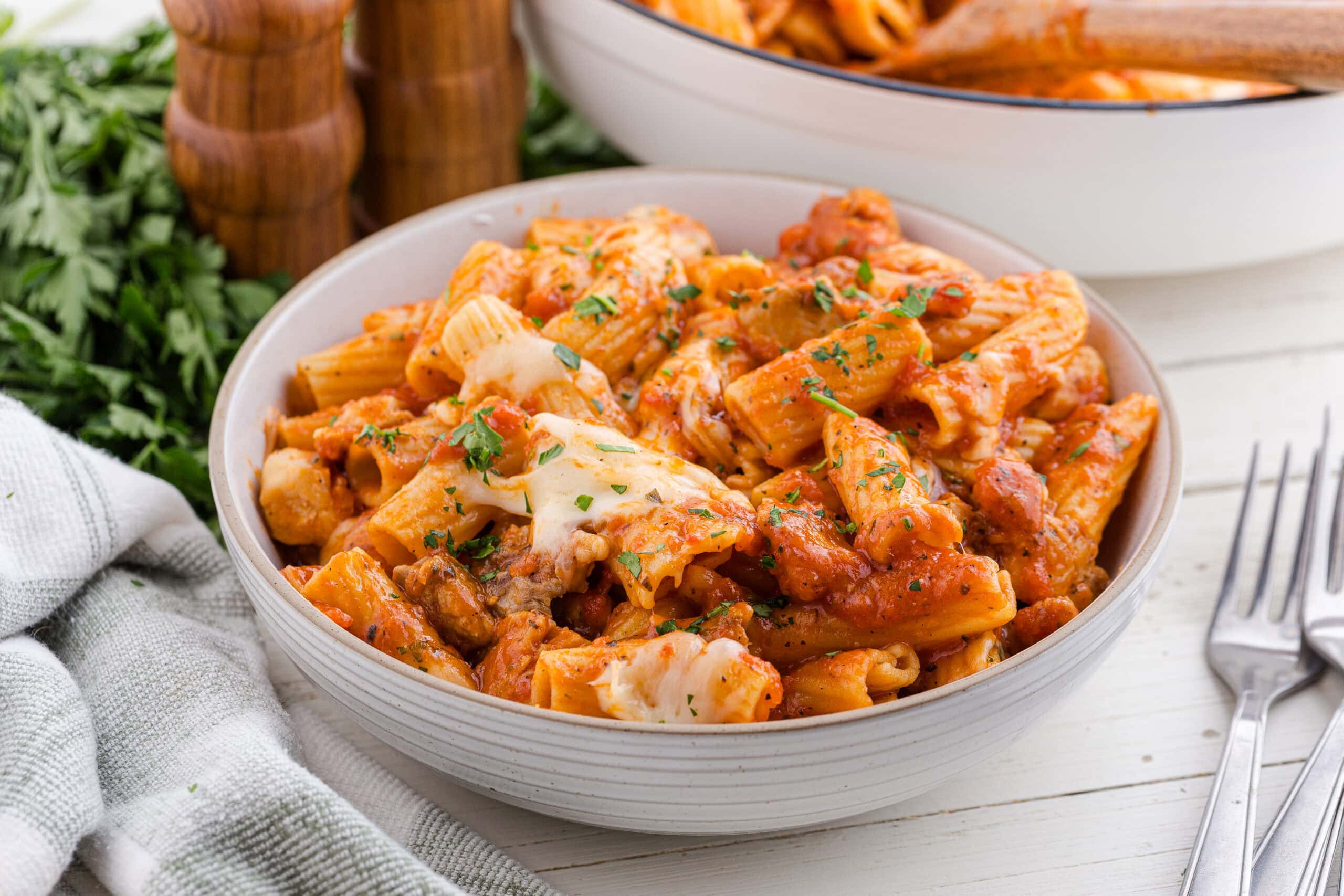 one pot chicken parmesan pasta recipe in a white bowl with forks and a napkin