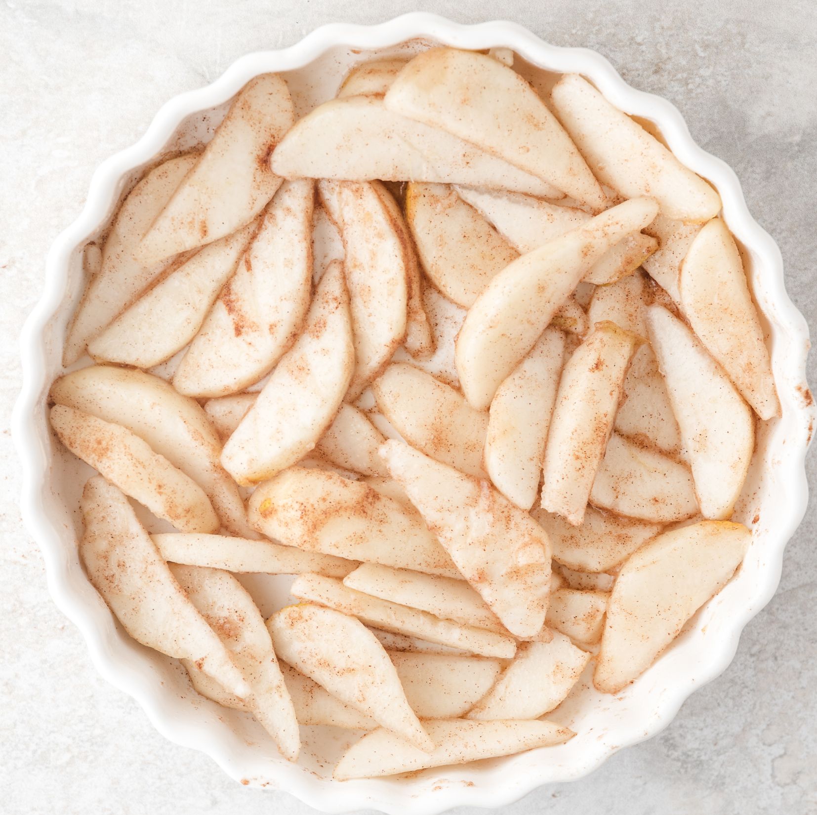 Fresh pears in pie plate with cinnamon sprinkled over them