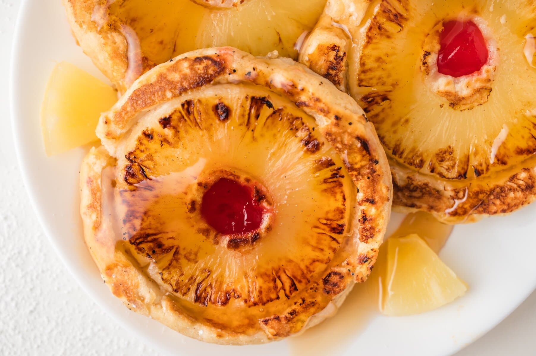 a close up of one pineapple upside down pancake topped with maple syrup