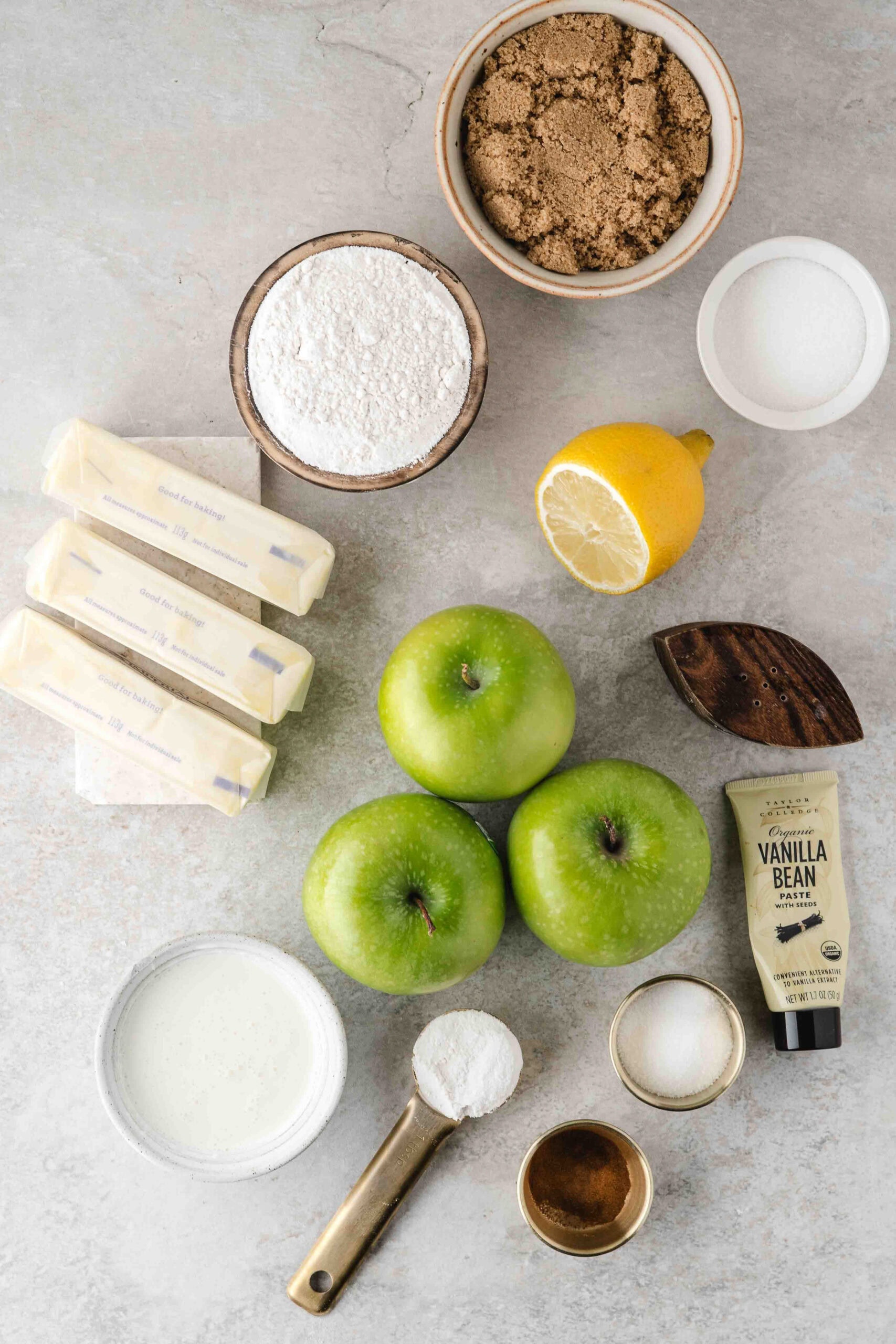 All ingredients to bake Apple Crisp Shortbread bars: apples, vanilla bean, butter, lemon, sugar, salt, milk.