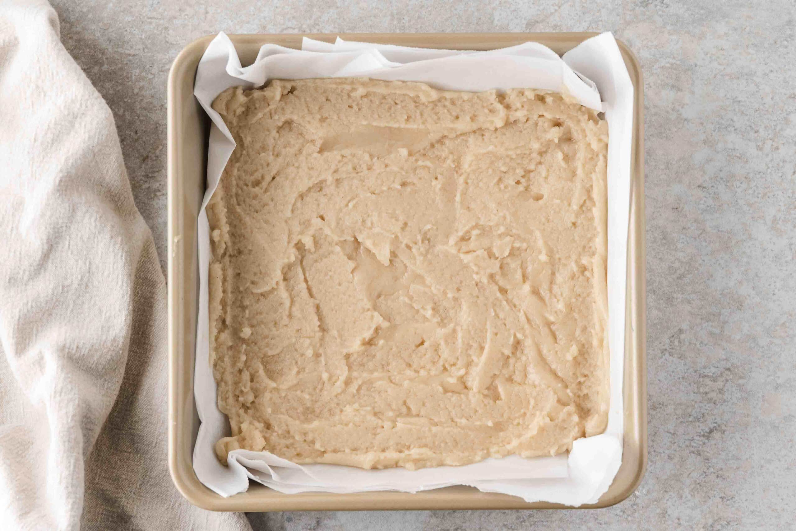 Shortbread layer for the apple crisp bars is placed in pan ready to be baked