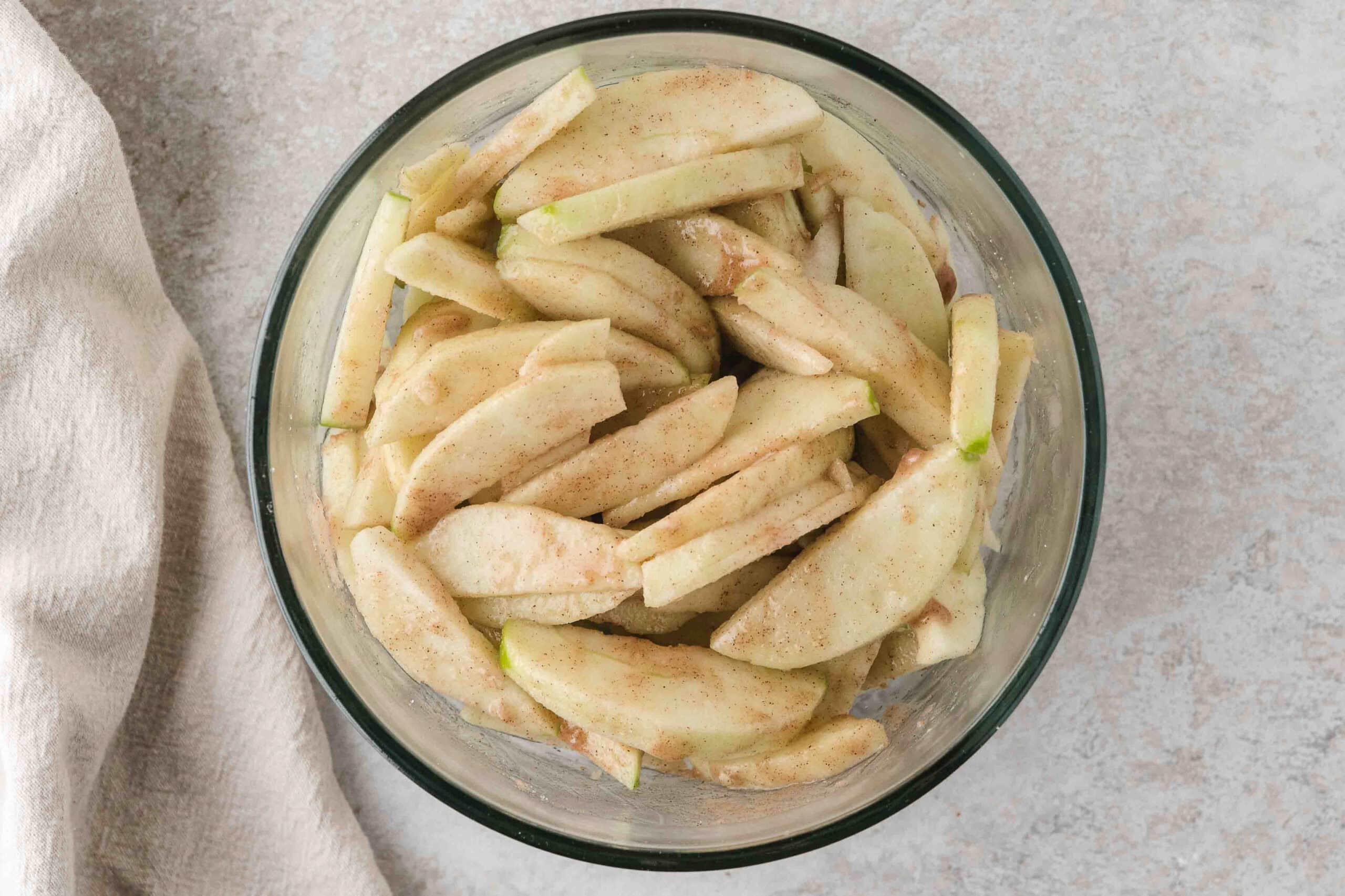 Apples tossed in a bowl with cinnamon and lemon juice