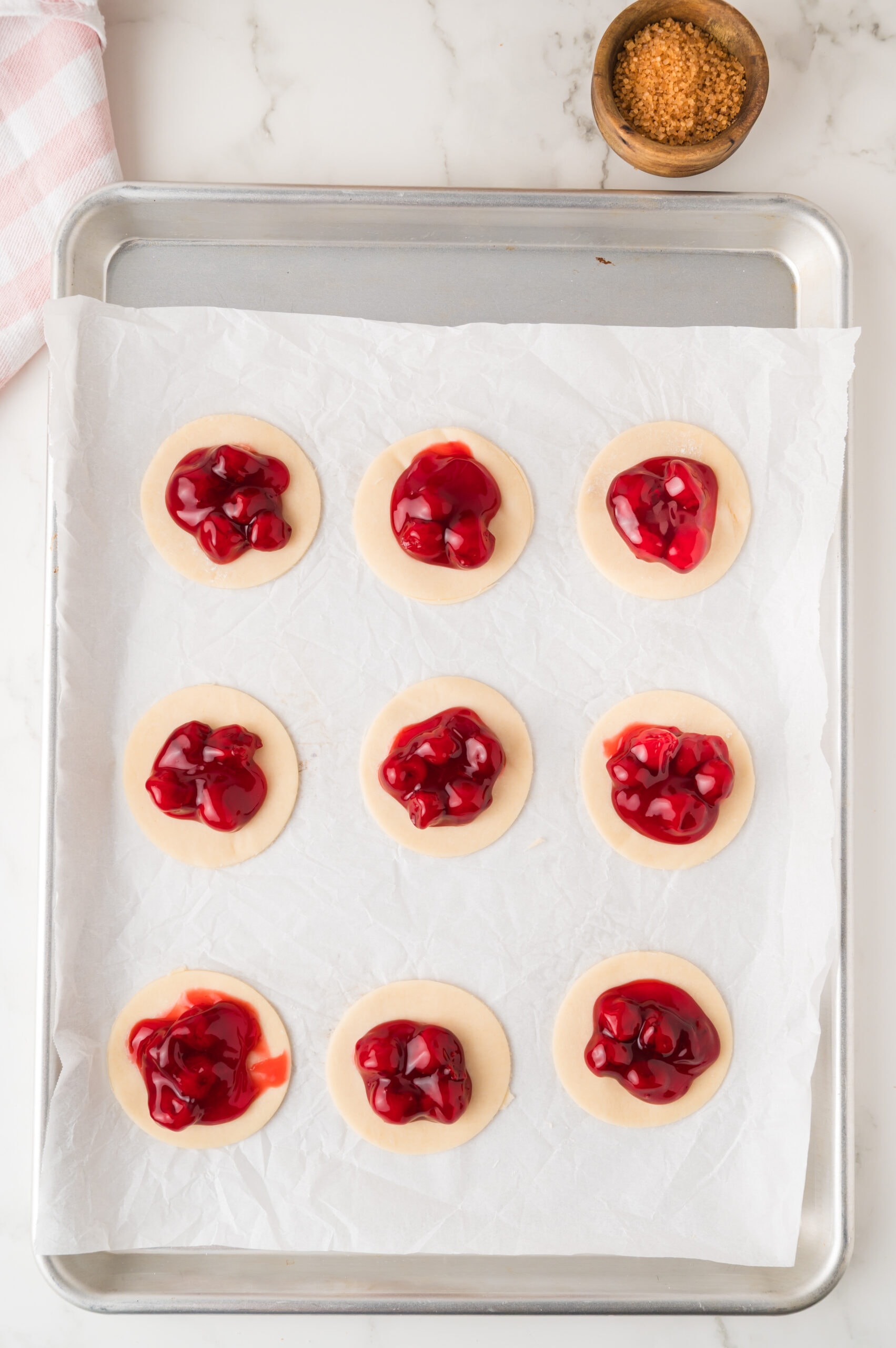 Cherry Pie Filling on top of cookie dough that are in a shape of a circle
