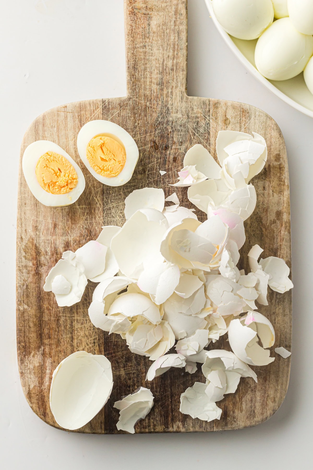Instant Pot hard boiled eggs with easy peel shells in a large pile on a cutting board