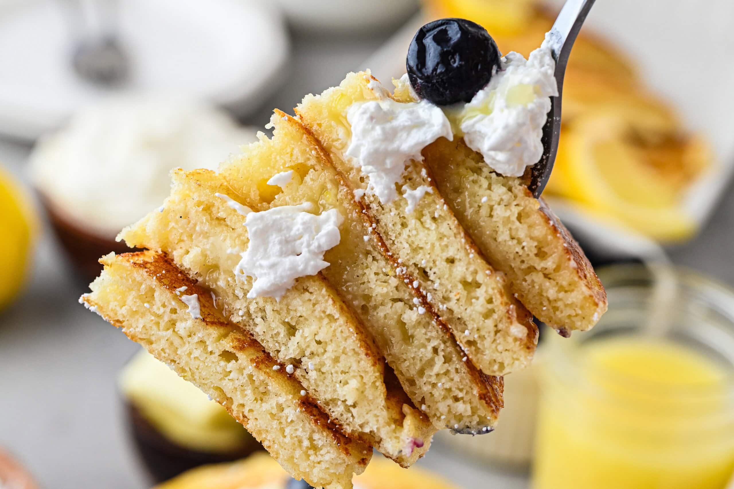 Close up of cut lemon ricotta pancakes, on a fork to be eaten