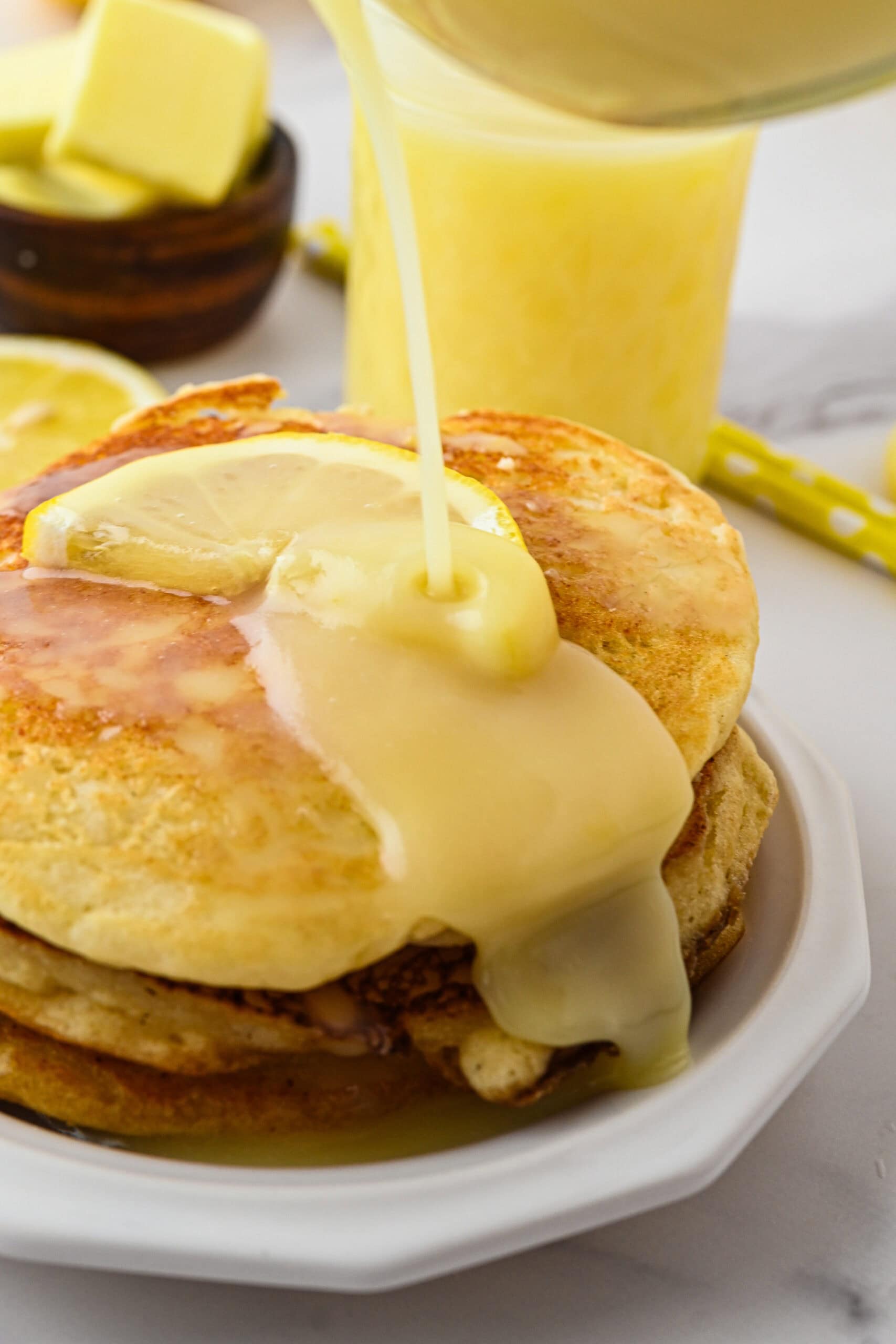 Lemon syrup being poured on top of a stack of pancakes to enjoy