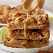 a close up of A stack of three apple crisp shortbread bars with a drizzle of caramel sauce on top