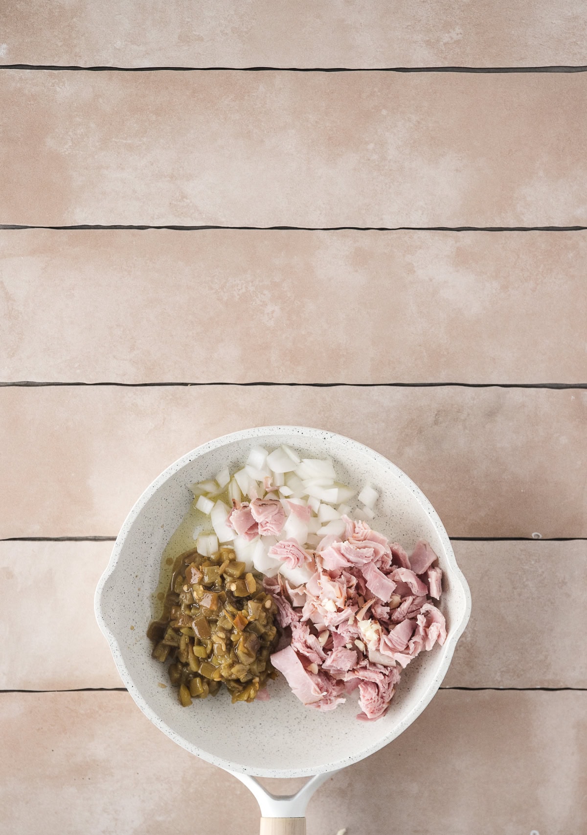 Ham, onion, garlic, spices, eggs, and green chilis to saute pan to cook together