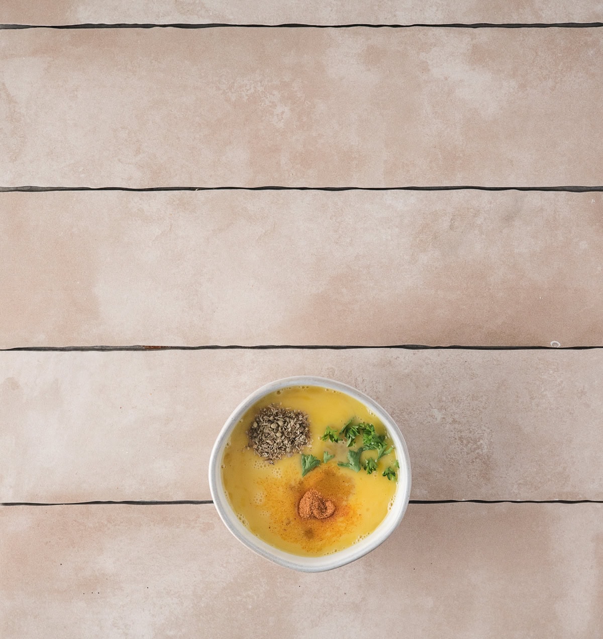 Eggs mixed with spices to be poured into the meat mixture in saute pan