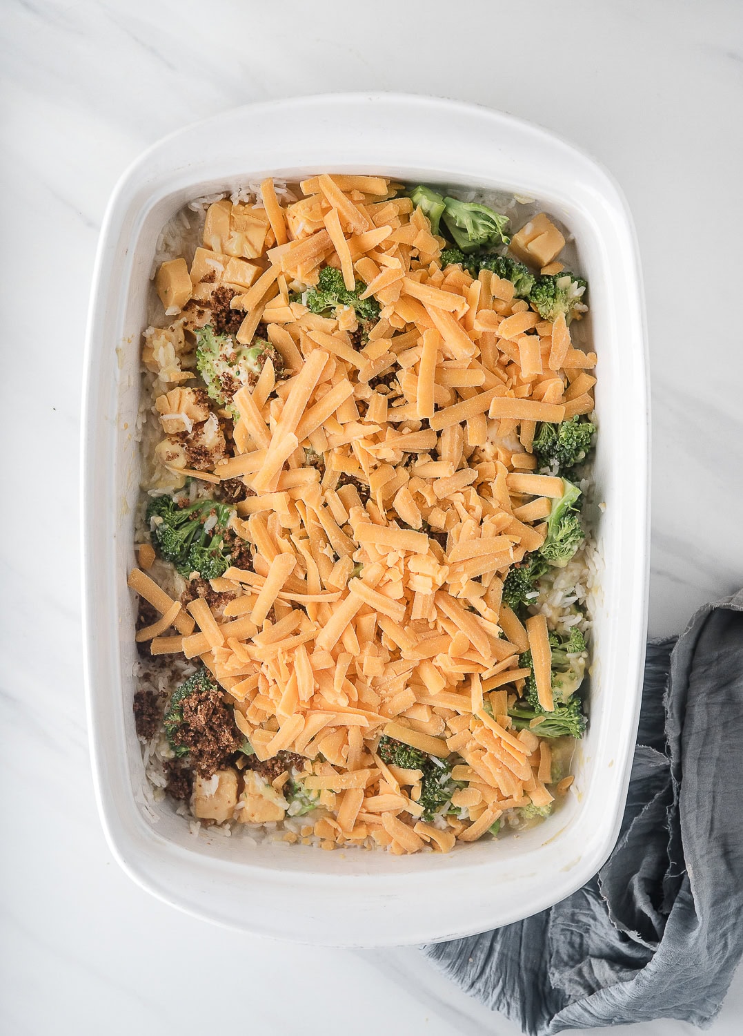 broccoli cheese and rice casserole topped with shredded cheddar cheese, right before baking