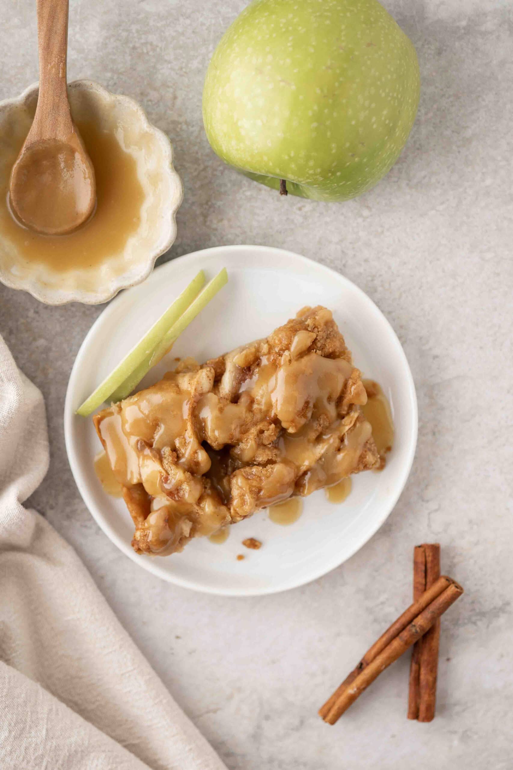 one slice of apple crisp shortbread bar with a drizzle of caramel sauce on top