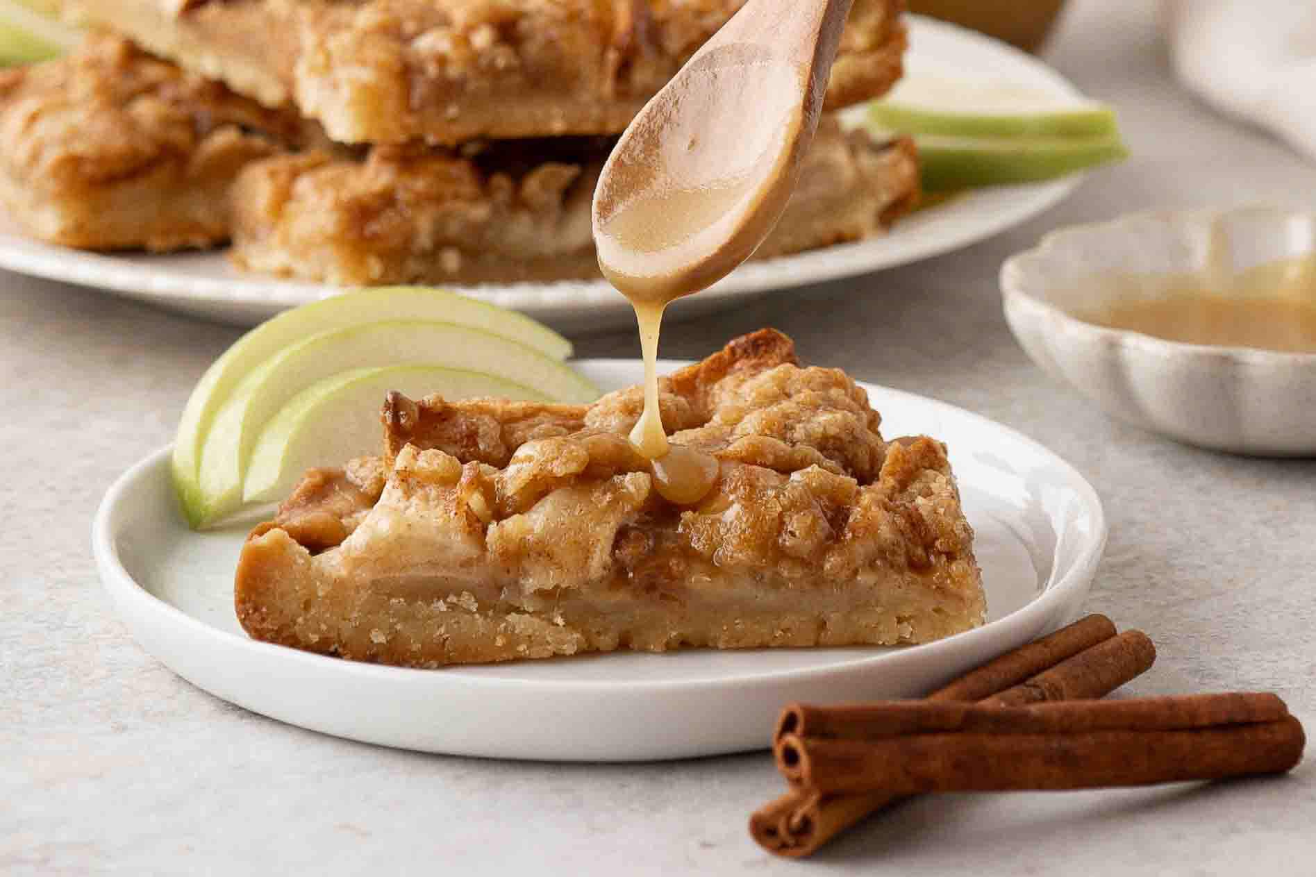 Side view of a apple shortbread bar with a drizzle of caramel sauce