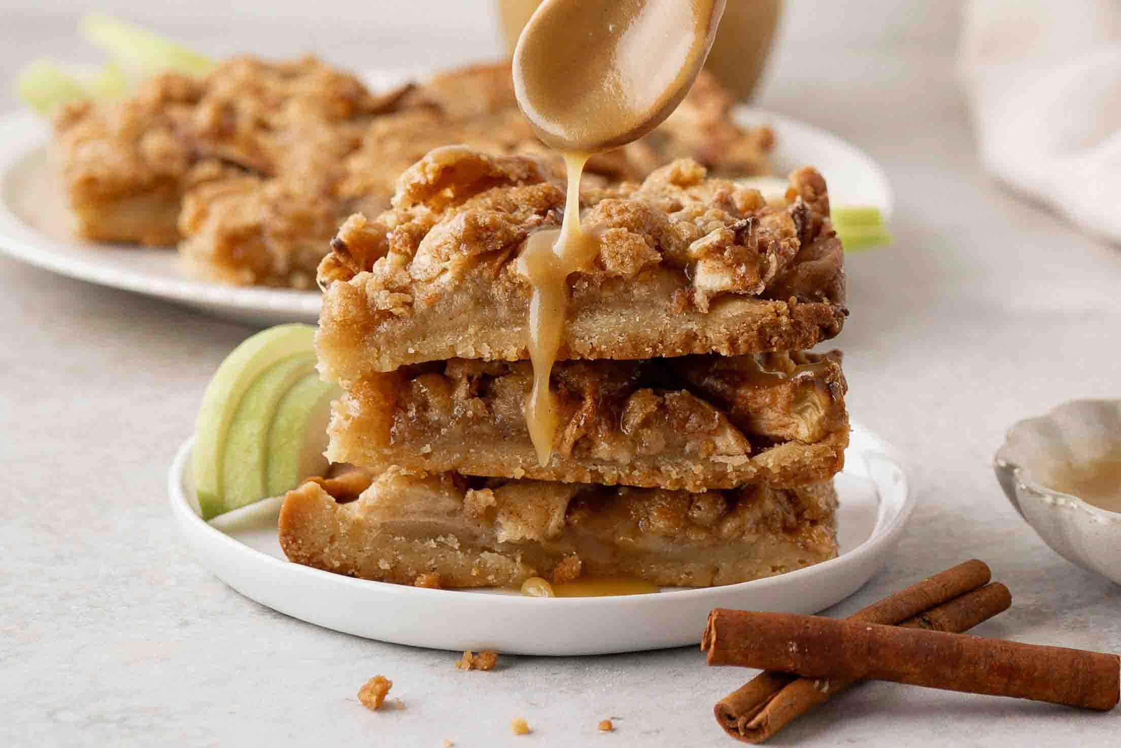 A stack of three apple crisp shortbread bars with a drizzle of caramel sauce on top
