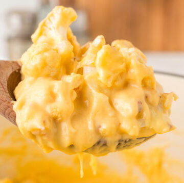 Close up of homemade cauliflower mac & cheese being lifted from the mixing dish