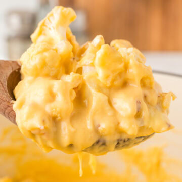 Close up of homemade cauliflower mac & cheese being lifted from the mixing dish
