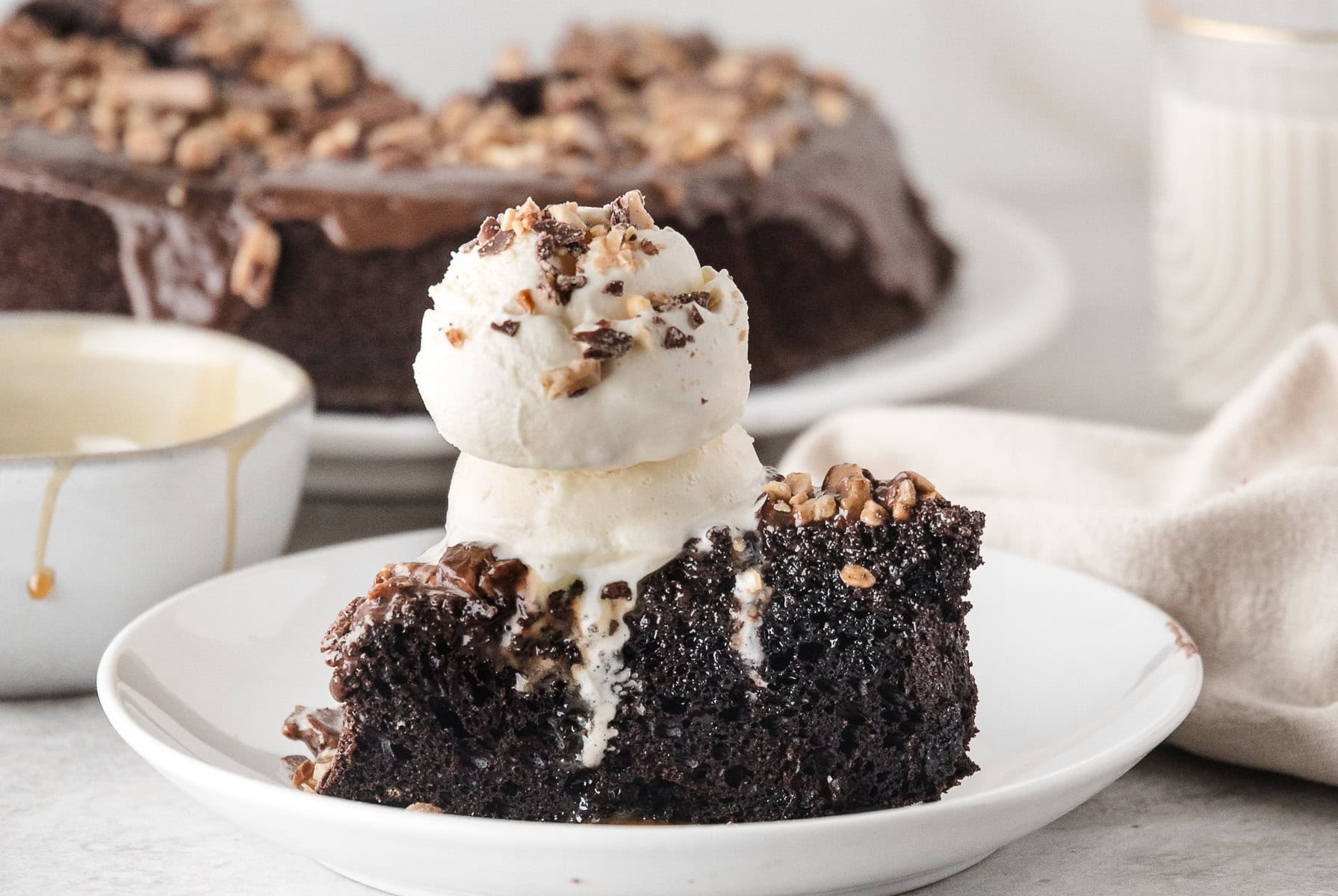 one slice of chocolate turtle cake topped with vanilla ice cream and chopped pecans