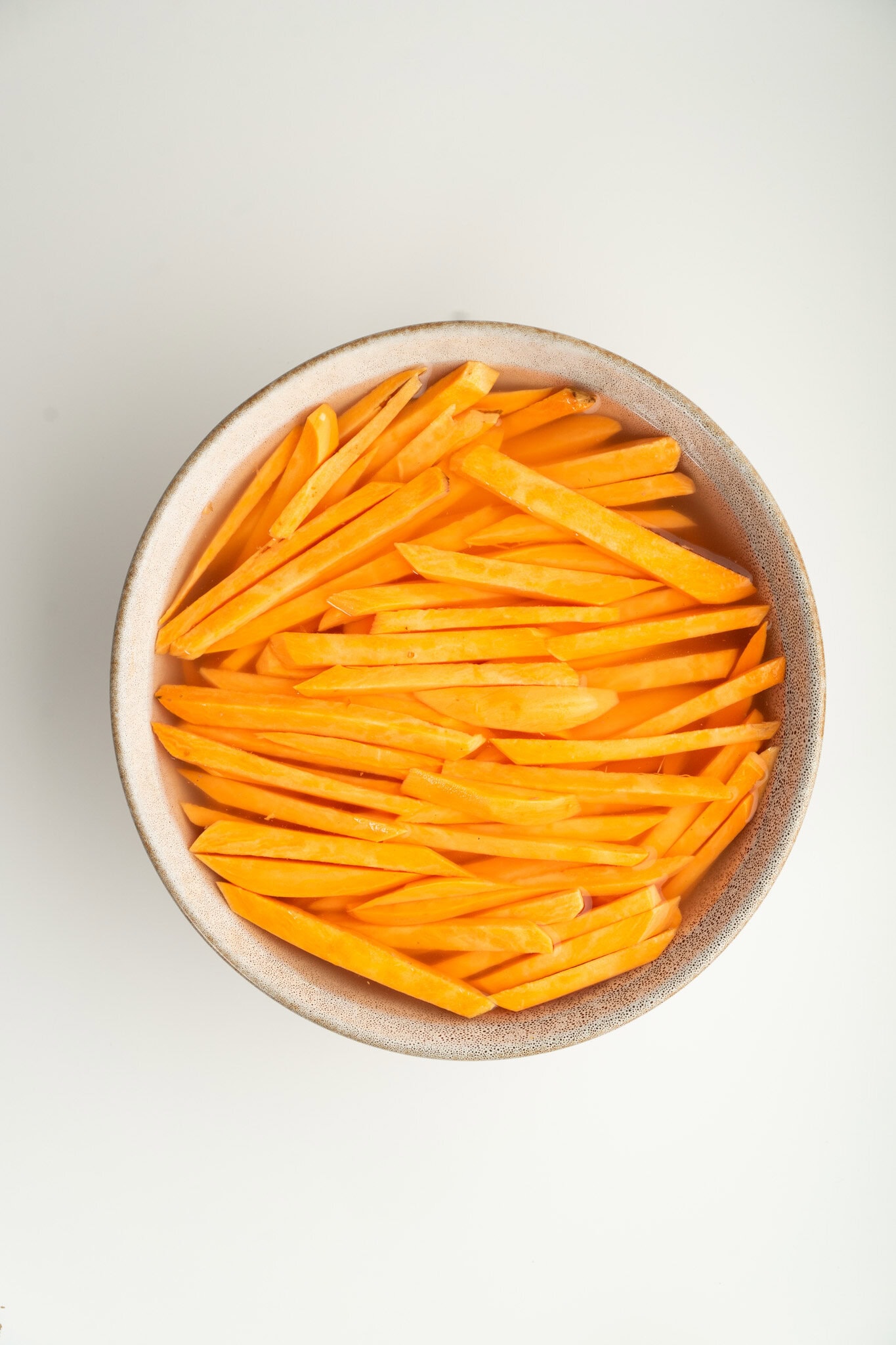 Sweet potatoes are shown cut in even slices to make crispy fries