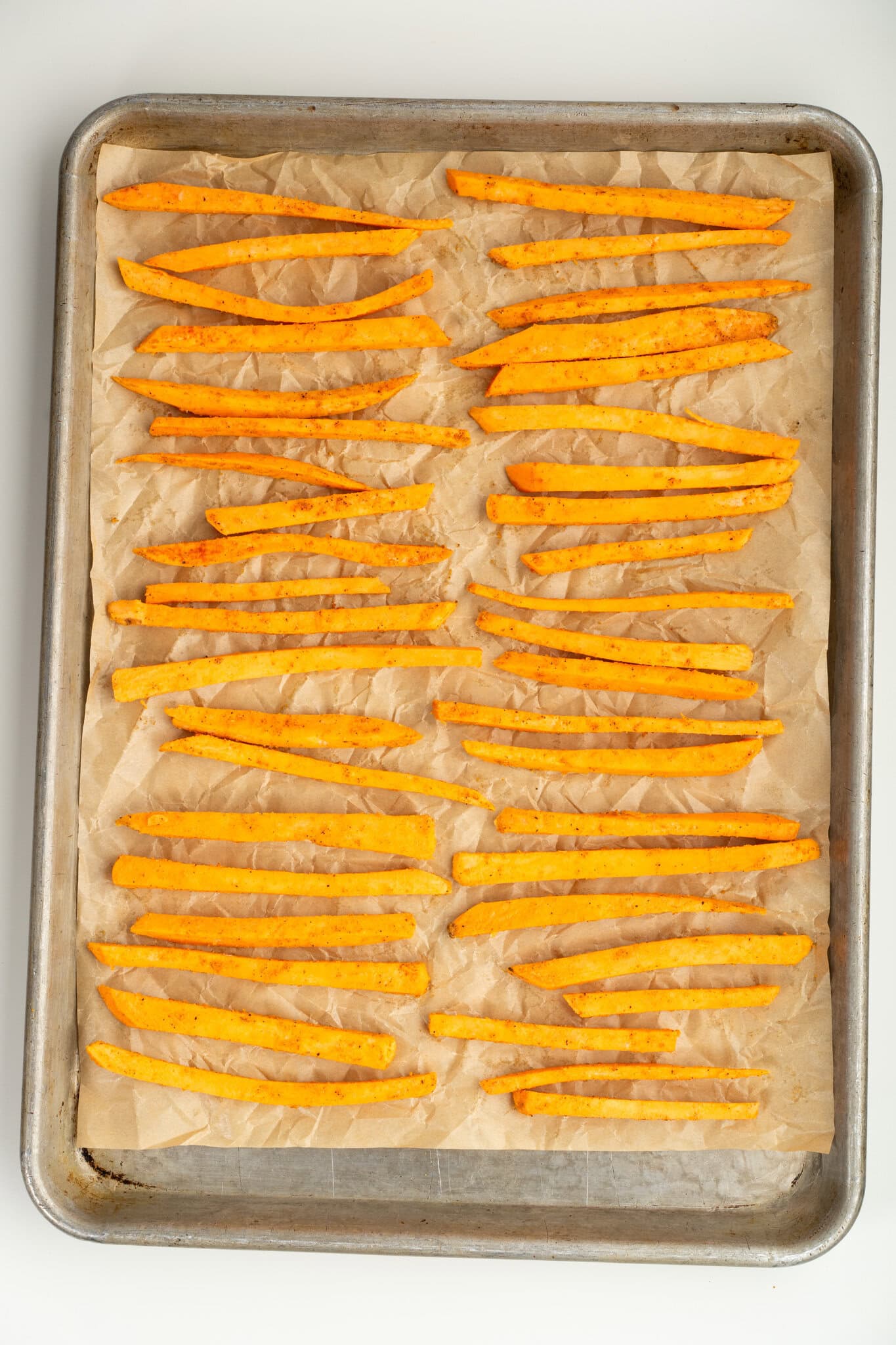 Sweet Potato slices dry and placed on baking sheet, oil and spices and cornstarch are added