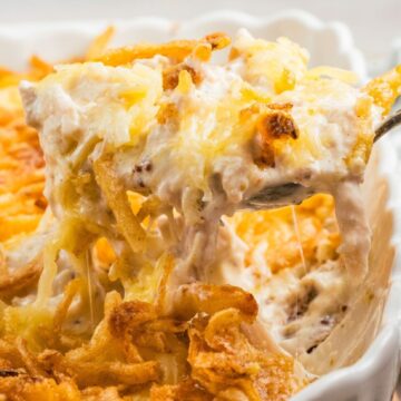 Scooping out the casserole with a large spoon to be plated