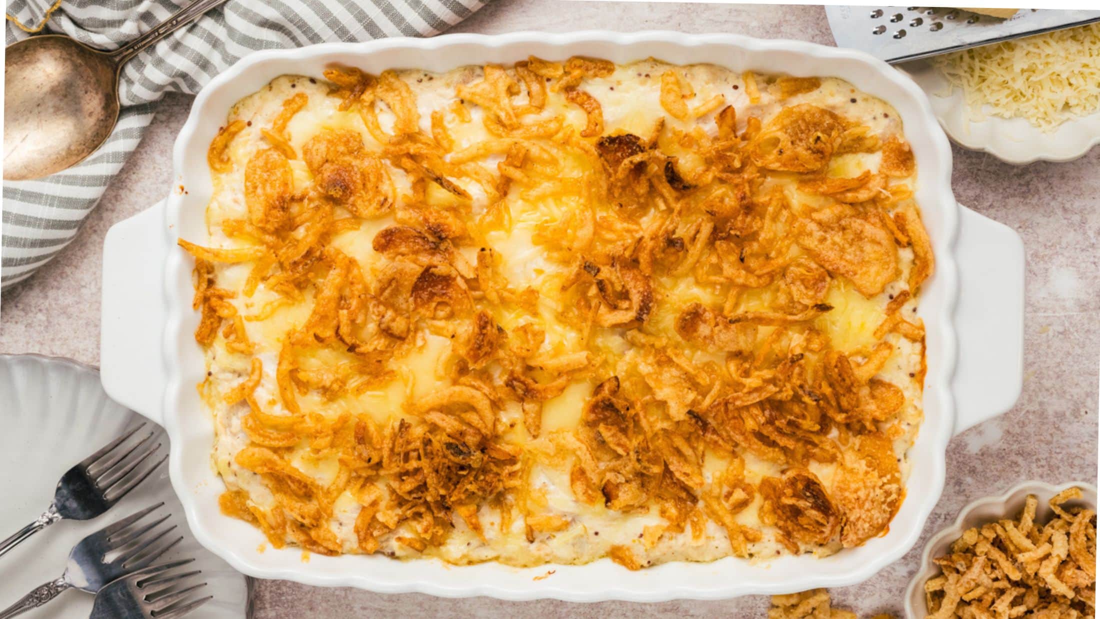 French Onion Chicken casserole ready to be served. Forks. plates to the side and extra fried onions to add to your plated casserole.