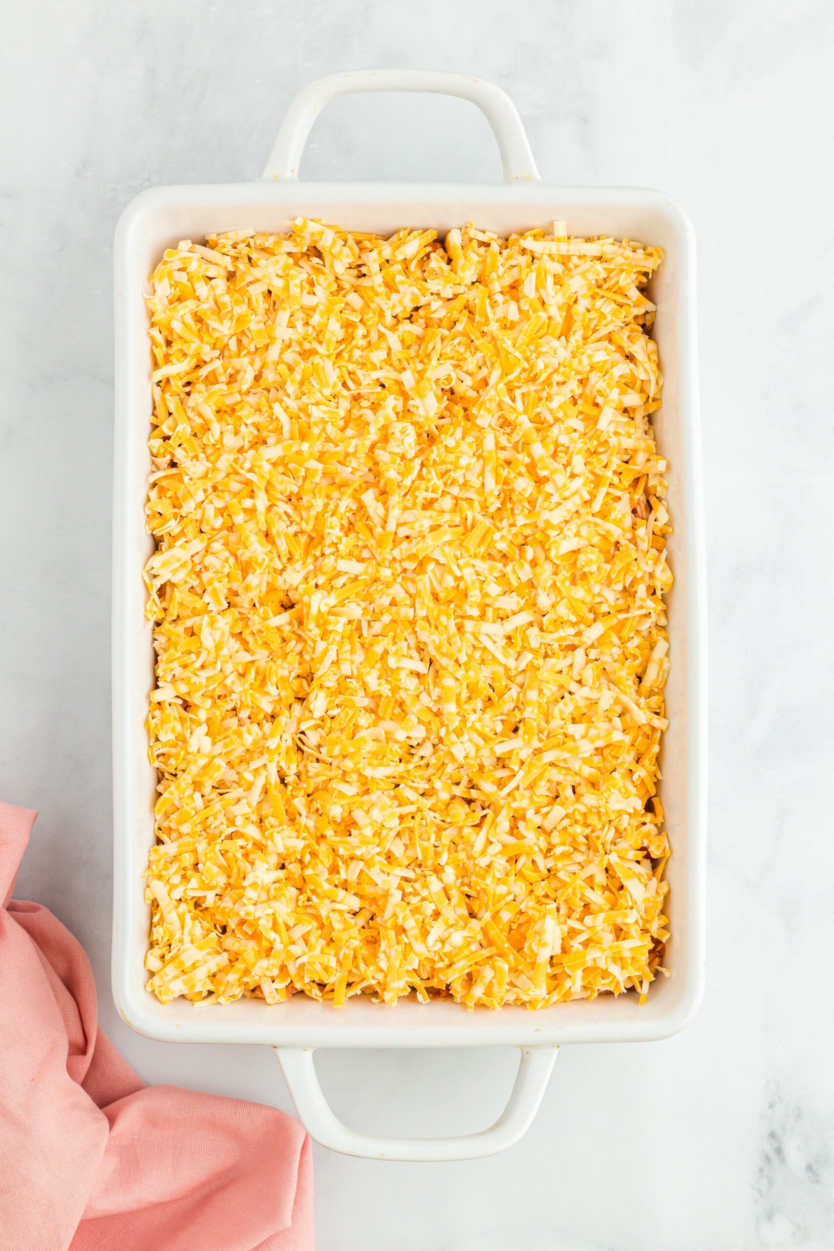 In the baking dish, topped with chicken over the beans and corn and cheddar cheese on top. Ready to bake.