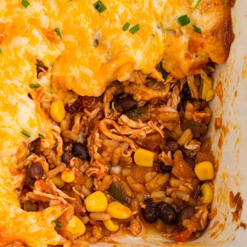 A scoop is taken out of the Mexican Chicken Rice casserole to show all the layers