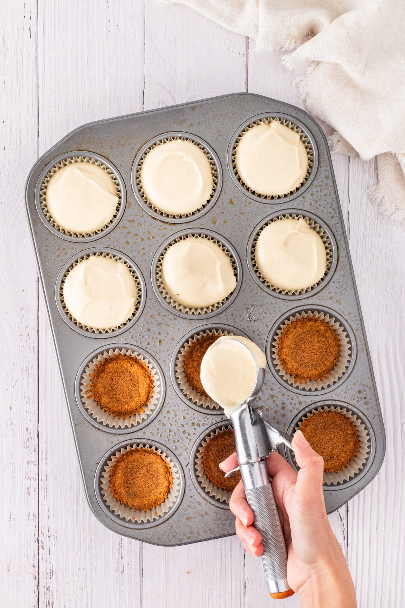 Scooping cheesecake batter on top the graham cracker layer