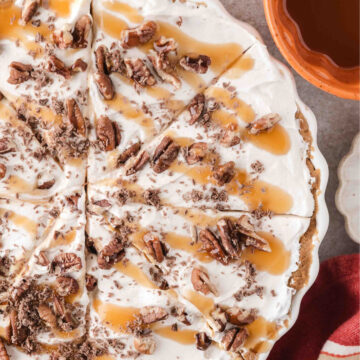 no bake pumpkin pie topped with whipped cream, caramel sauce, and chopped pecans