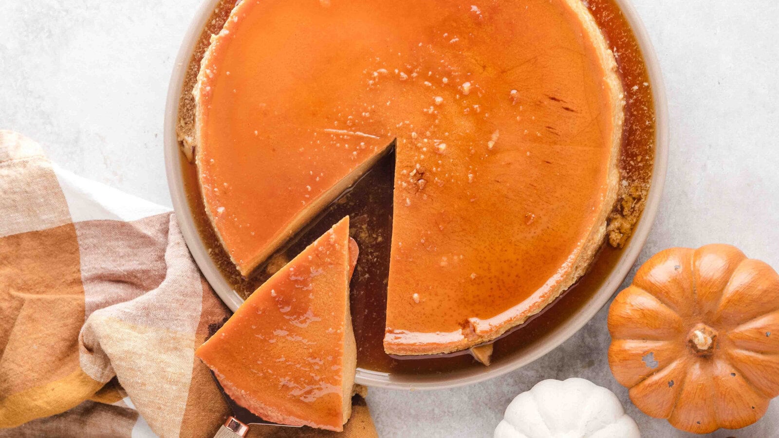 a large pumpkin flan with one slice being lifted out