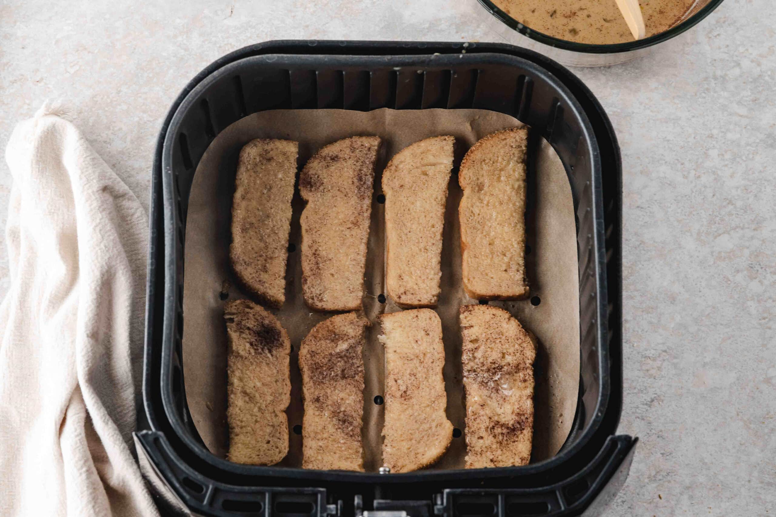 French toast sticks dipped in cinnamon batter and laid in the air fryer ready to be cooked