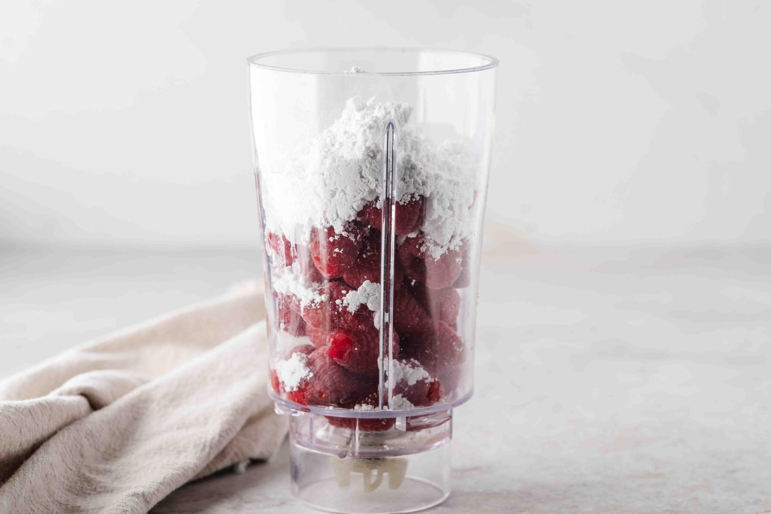 Raspberry sauce ingredients in a blender to blend together: powder sugar, lemon juice, raspberries