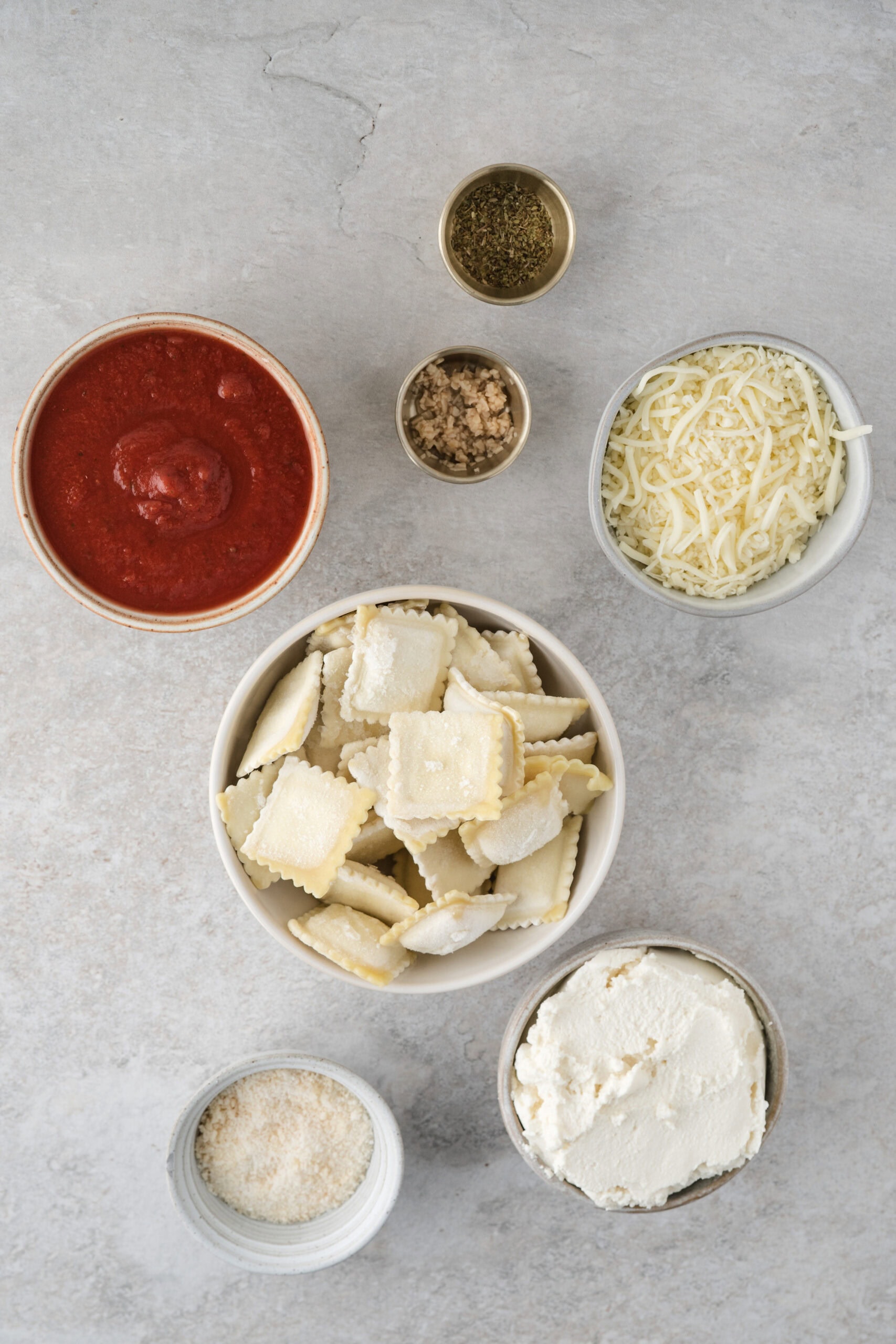 All ingredients shown: parmesan cheese, ricotta cheese, frozen (can use fresh) ravioli, tomato sauce, mozzarella cheese, Italian seasoning