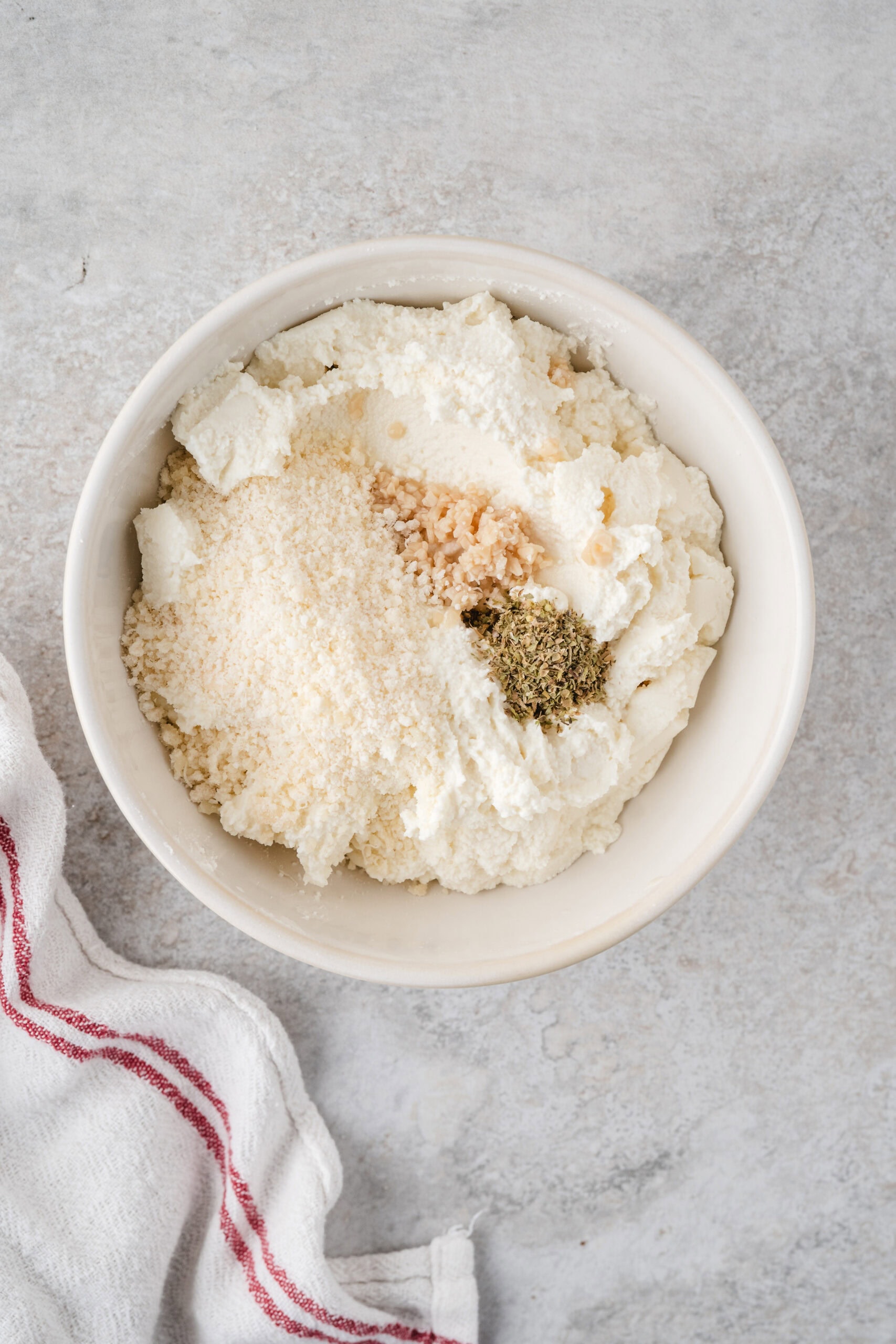 Process step of adding parmesan cheese with seasonings and ricotta cheese