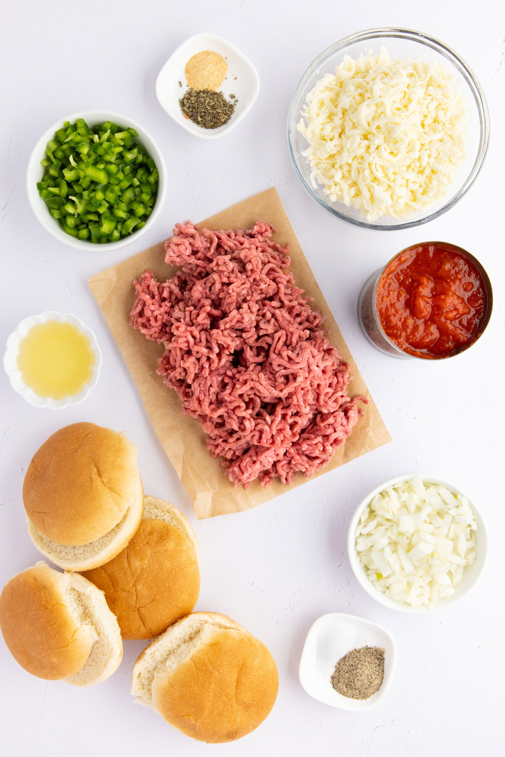 All ingredients pictured: ground beef, buns, pizza sauce, diced onions, diced green peppers, mozzarella cheese, olive oil, dried basil and garlic powder