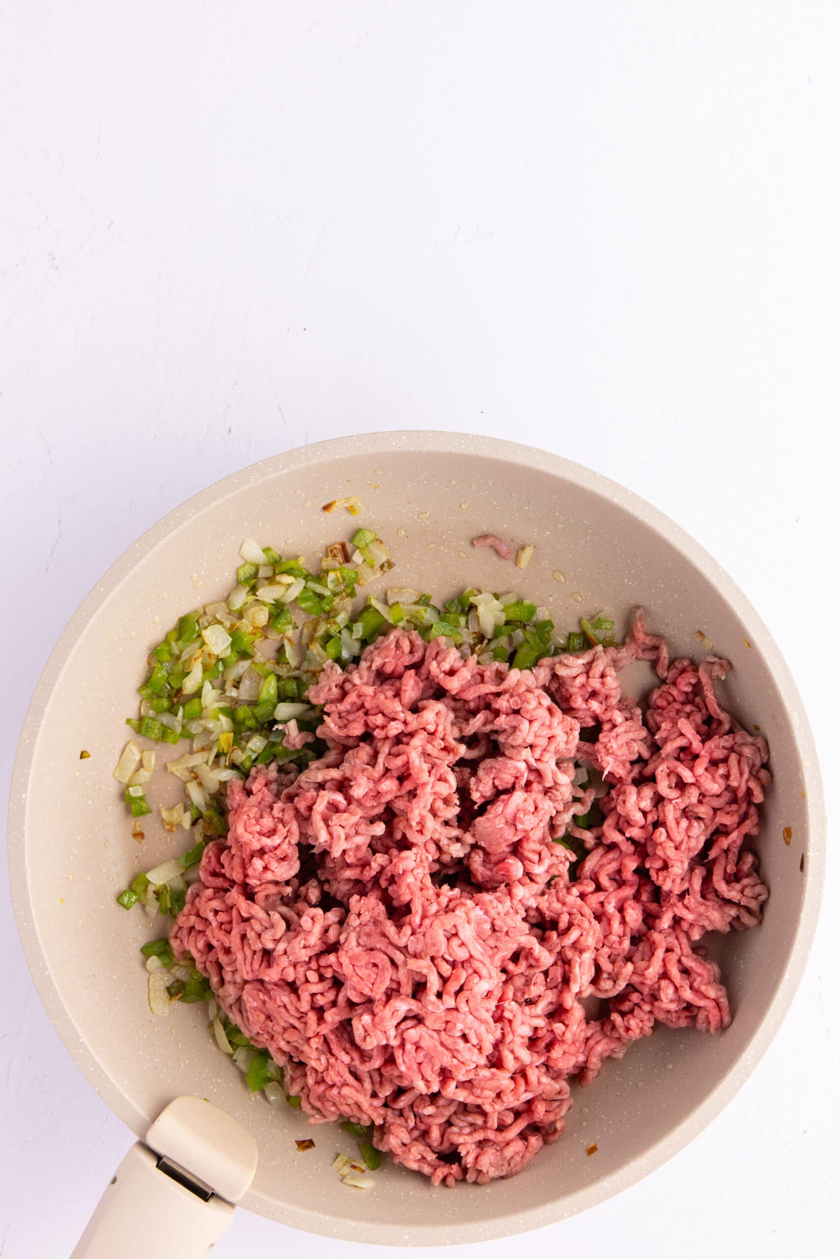 Adding ground beef to be cooked with diced onion and diced green pepper