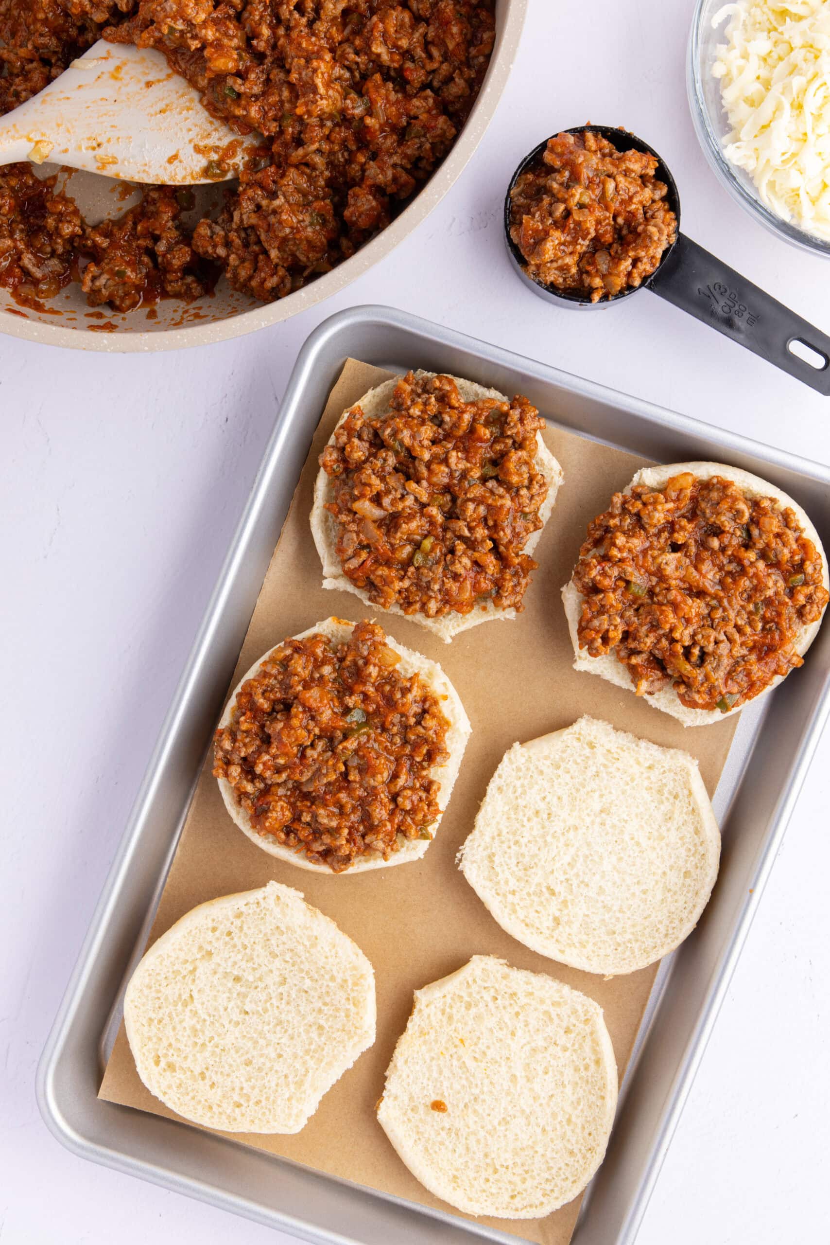 Adding the pizza burger ground beef mixture to top of the buns