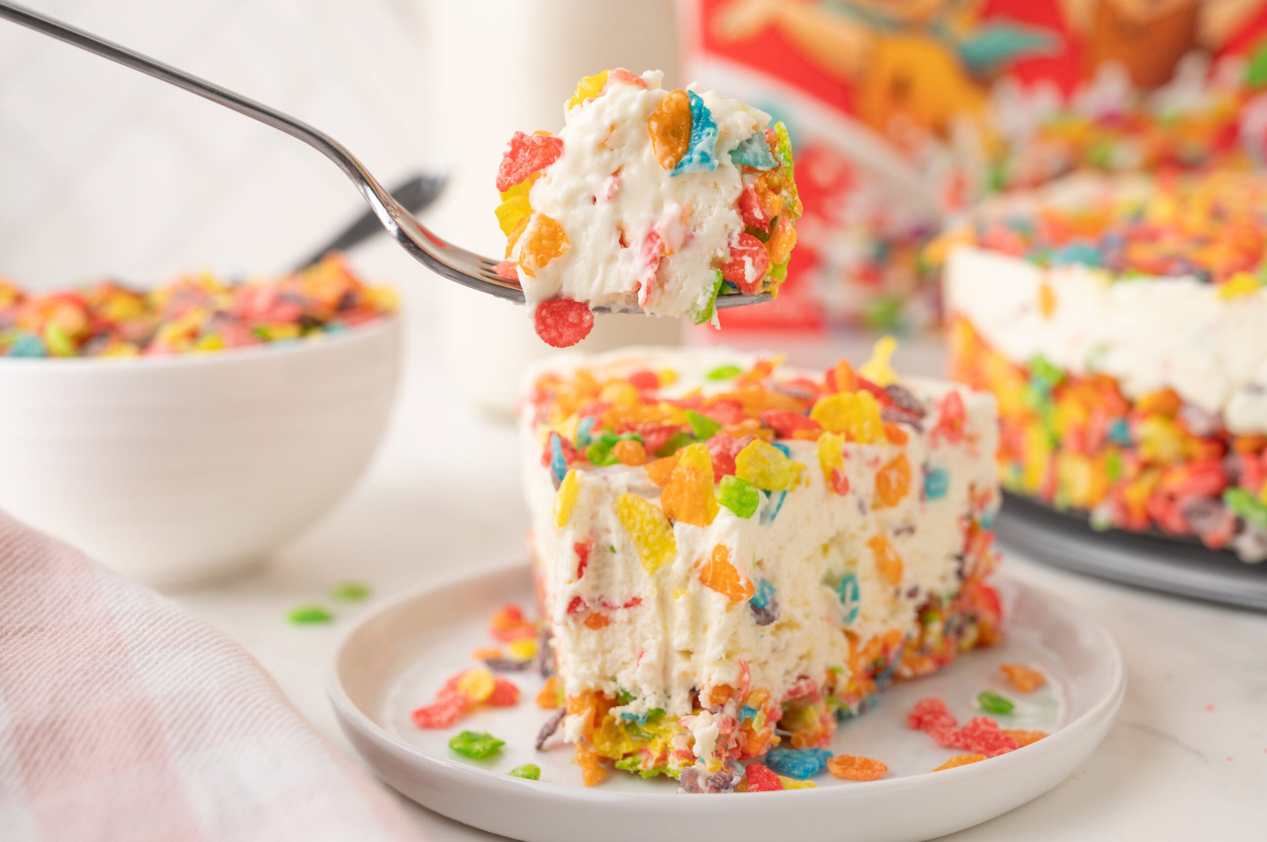 A slice of cheesecake with a a fork taking a piece to be enjoyed