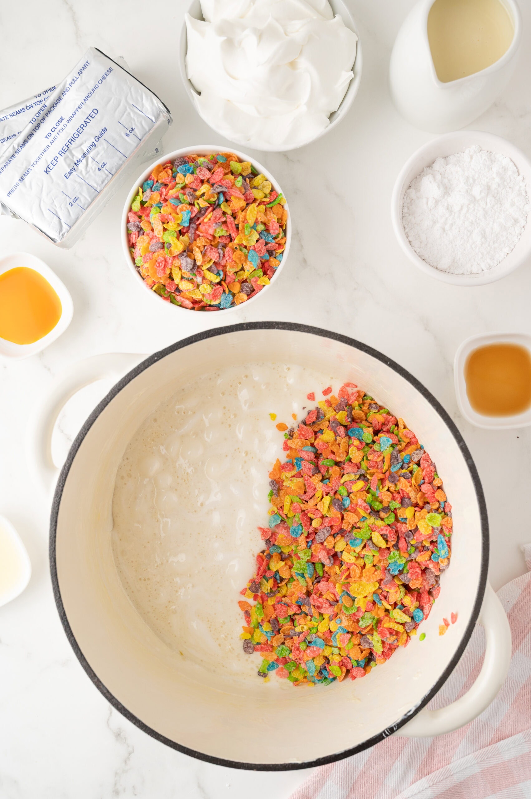The start of the process to make the fruity pebble cheesecake, all ingredients pictured around the mixing bowl