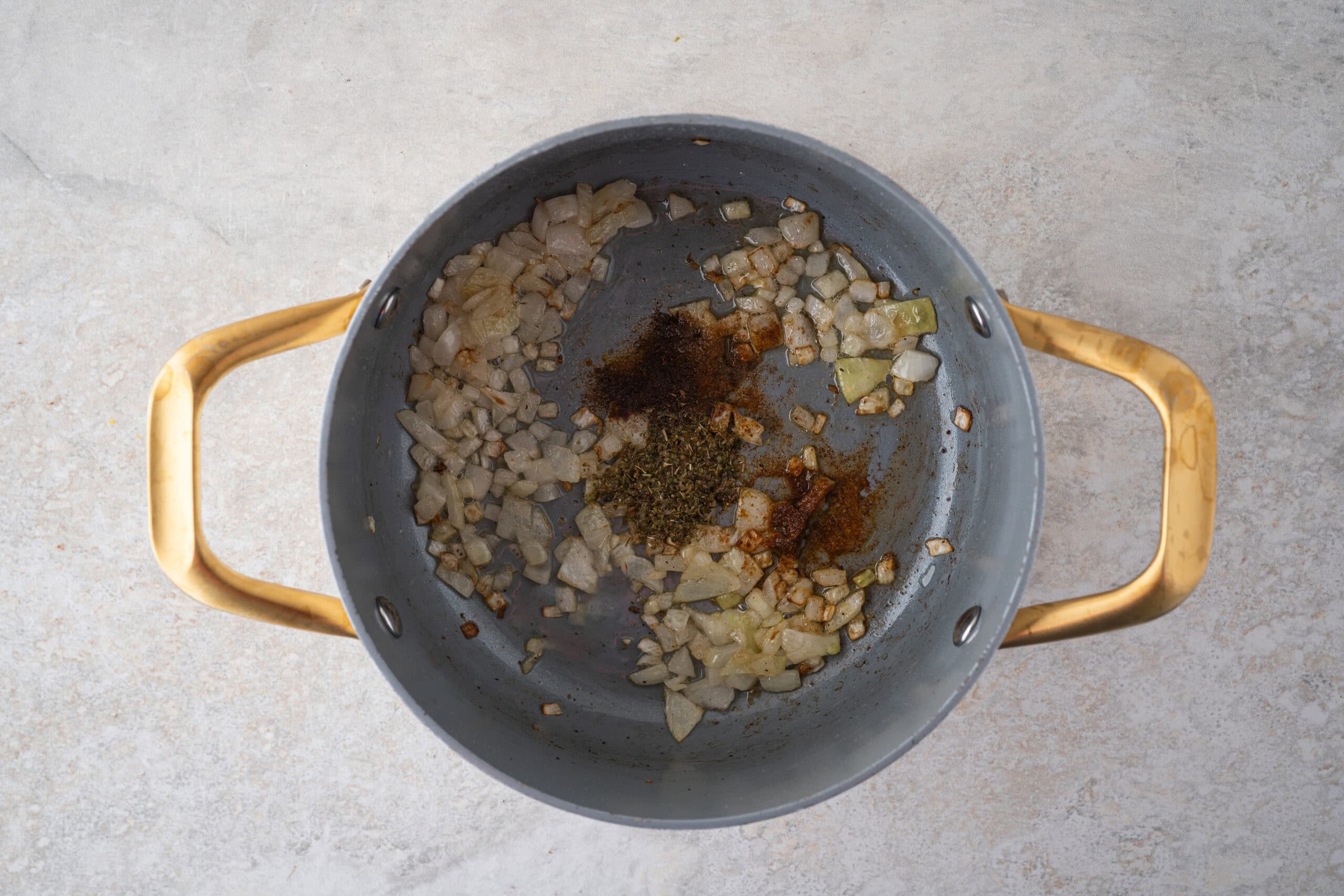 Sautéed onion with spices in pan, starting the process of making Mexican Rice and Beans