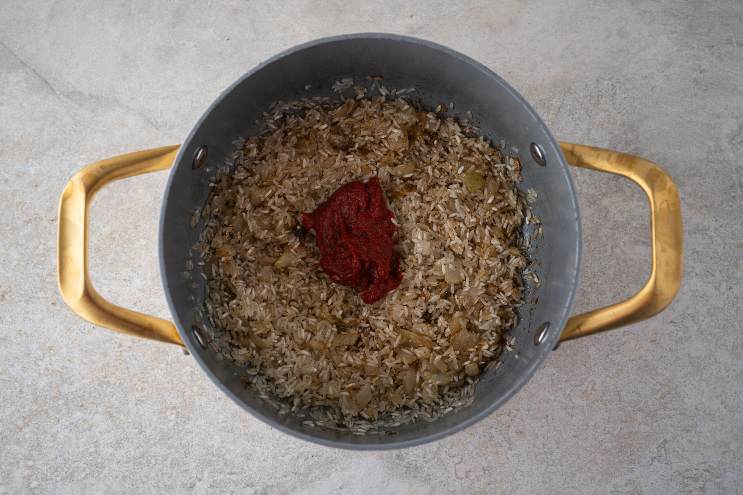 Rice added to the sautéed onions and adding in tomato paste
