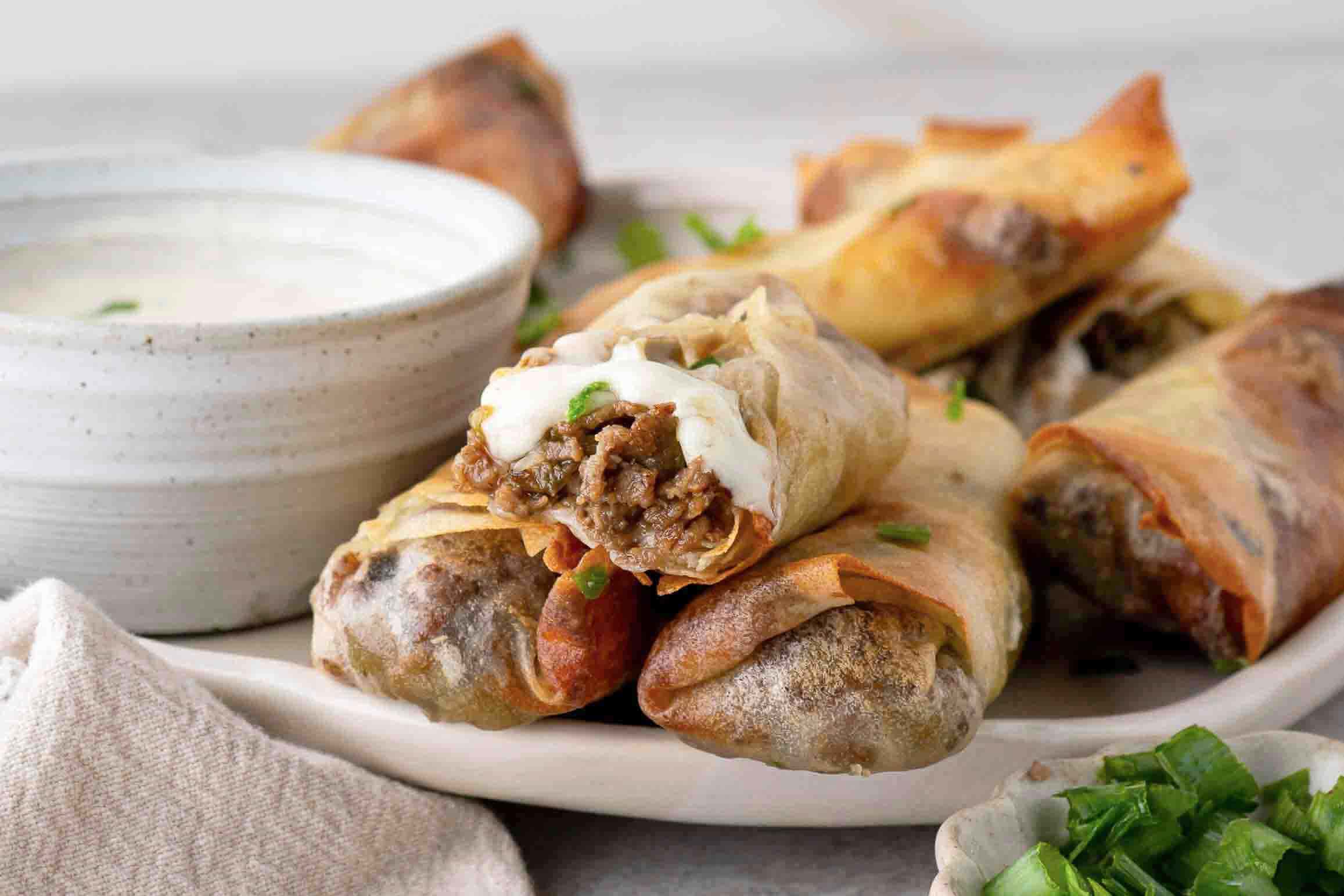 Inside of the philly cheese steak egg rolls, showing melty cheese and steak mix
