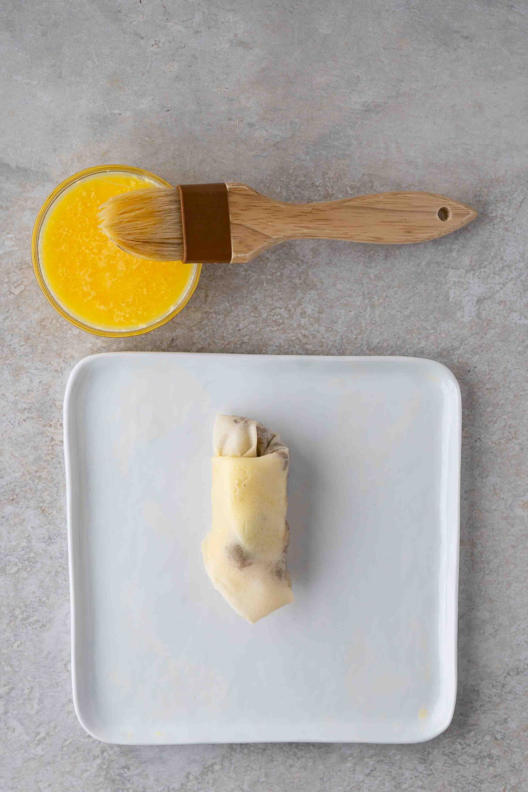 The process of the cheese steak egg roll is all rolled up brushed with an egg wash to be put in the air fryer