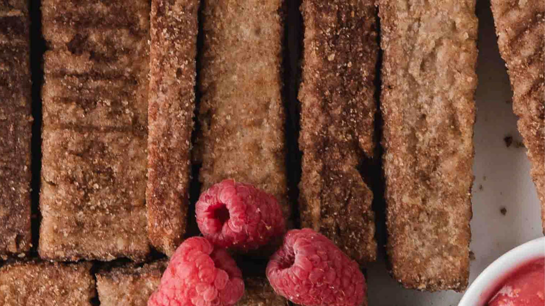 Air Fryer French Toast Sticks plated and ready to be enjoyed with homemade raspberry sauce