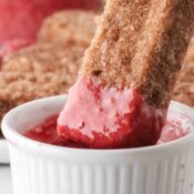 Air Fryer french toast stick being dipped in homemade raspberry sauce