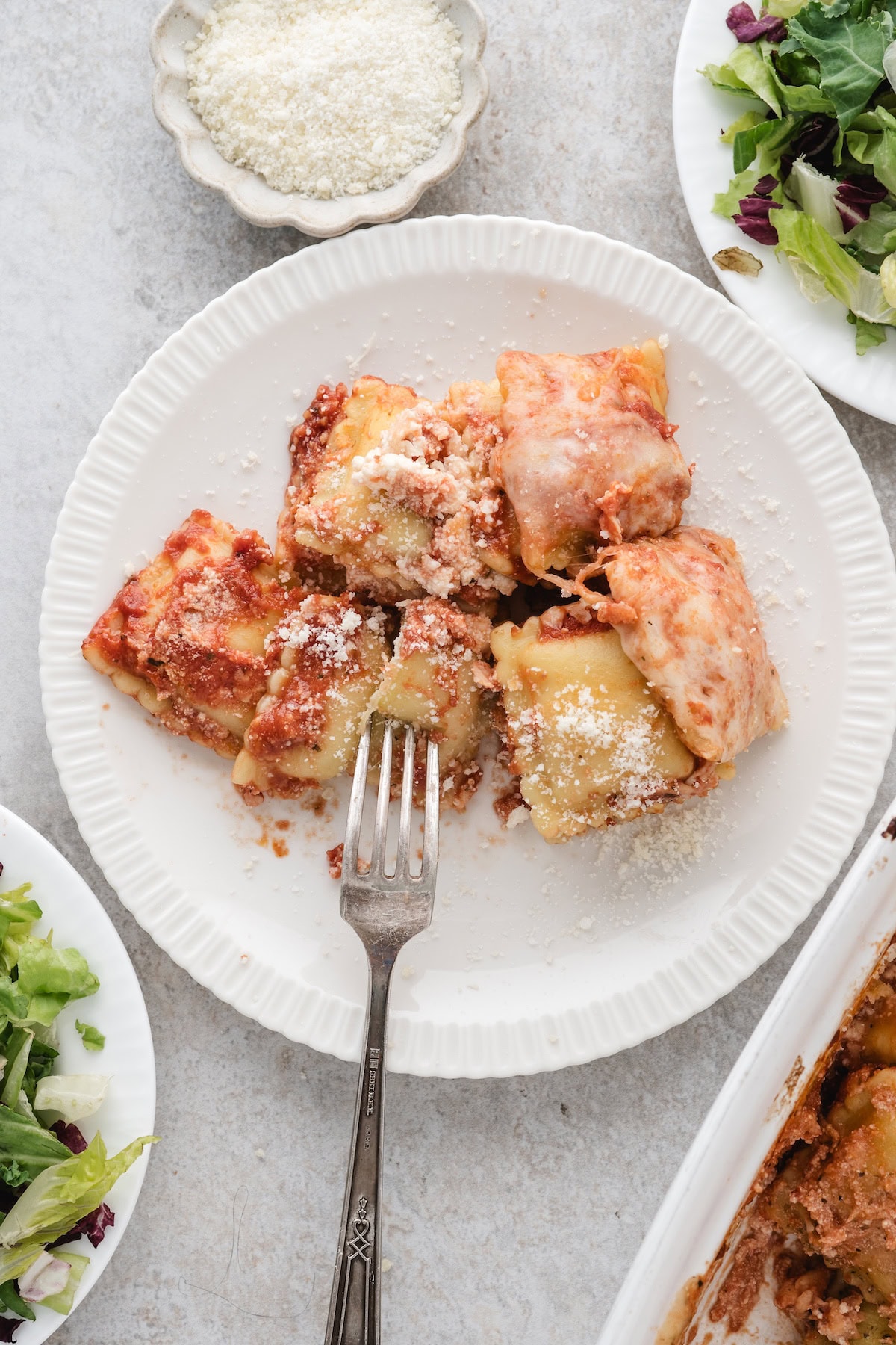 one serving of baked ravioli casserole on a white plate with a fork