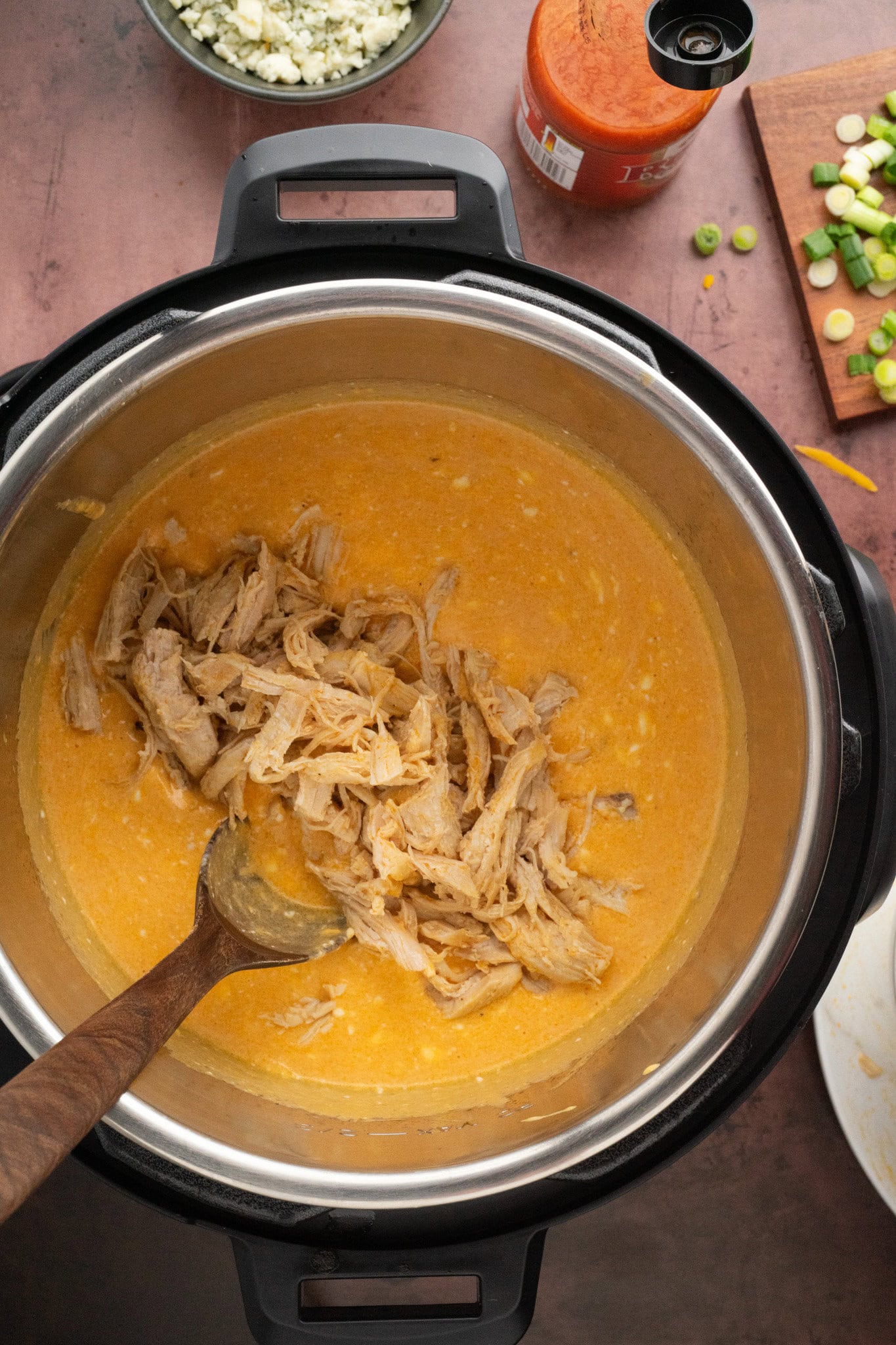 Adding the shredded chicken to the instant pot cheddar mixture