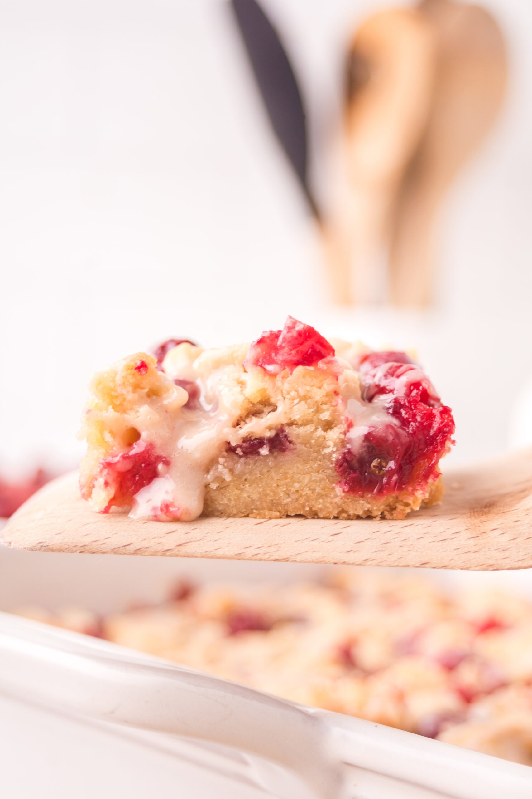 Close up of cranberry bar with icing dripping off the side