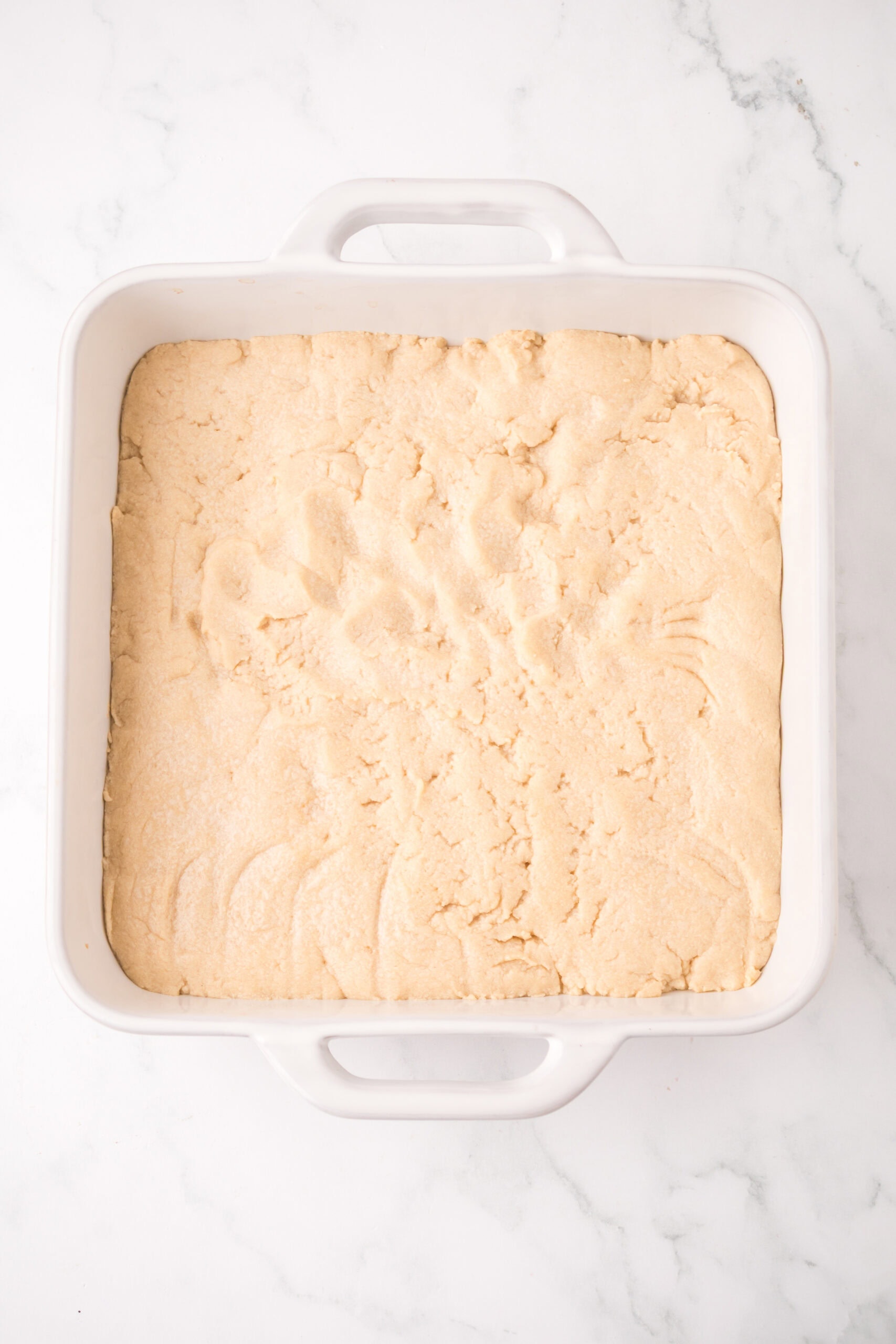 Process of cookie dough pressed into a baking pan