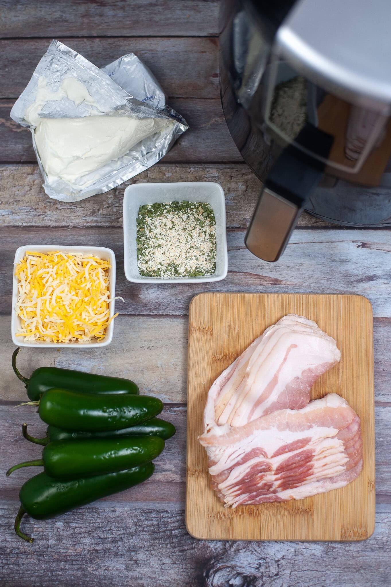 Ingredients to make jalapeno poppers in the air fryer: bacon, peppers, ranch seasonings, cheddar cheese, and cream cheese